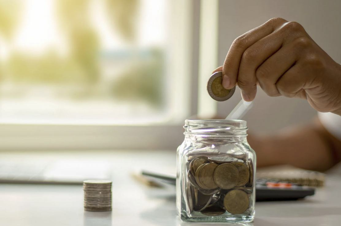 Persona ahorrando dinero en un frasco